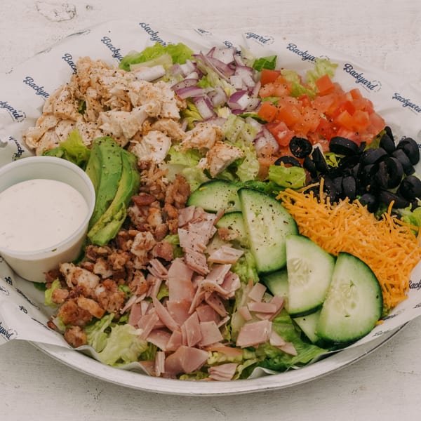 A Backyard on Broadway Cobb salad with chicken, ham, bacon, avocado, tomato, olives, cheese, and dressing.