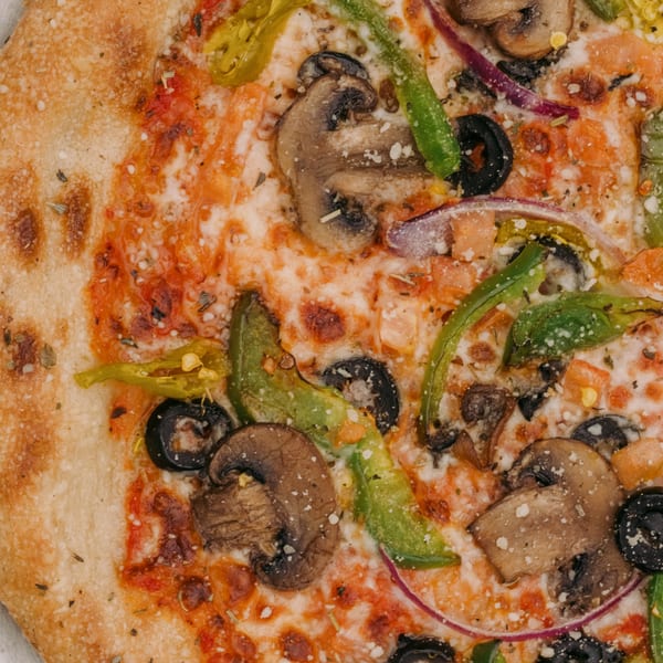 Close-up of a pizza with mushrooms, green peppers, black olives, and red onions.
